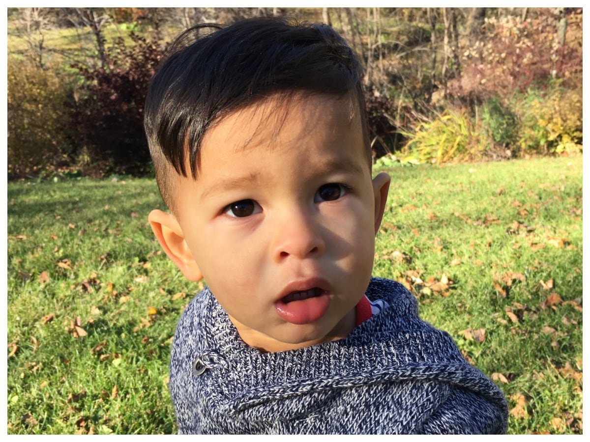 default-174 A boy sits outside on the grass and looks questioningly at the camera.